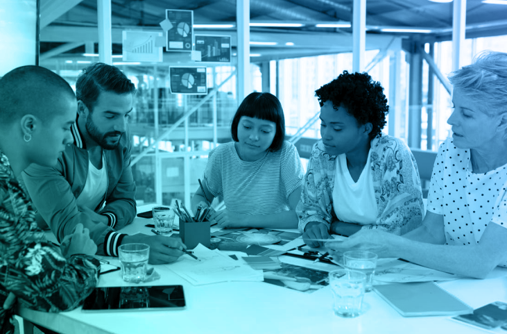 five people sitting at table - looking at paperwork on table